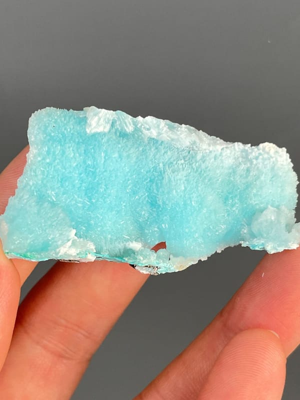 Turquoise-blue fibrous aragonite slab from Sichuan, China, held in hand
