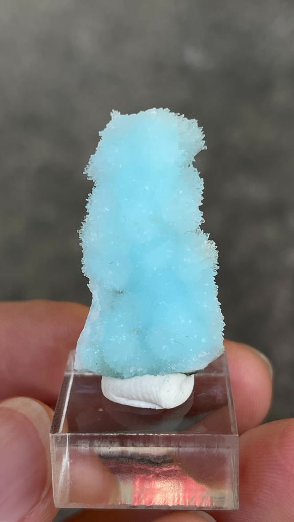 Sky-blue needle aragonite crust from Yunnan, China, on an acrylic stand