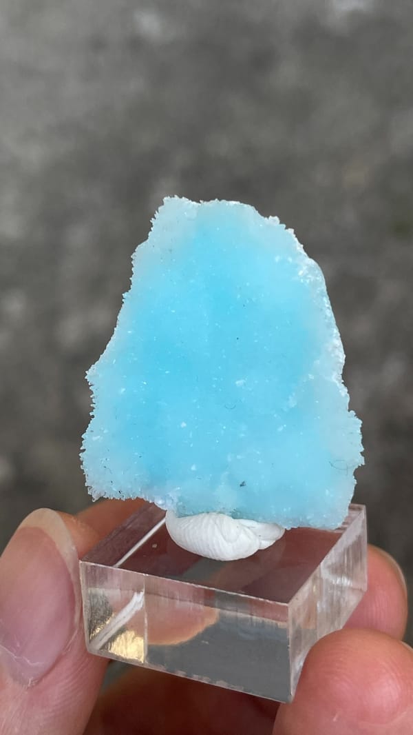 Sky-blue fibrous aragonite crust from Yunnan, China, on an acrylic stand, close-up of the crystal faces