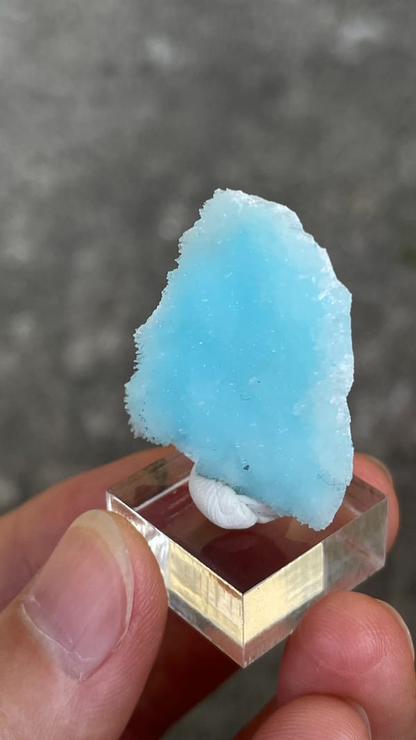Sky-blue fibrous aragonite crust from Yunnan, China, on an acrylic stand, top view