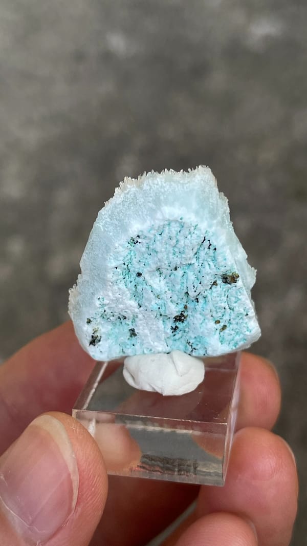 Sky-blue fibrous aragonite crust from Yunnan, China, on an acrylic stand, detail of the matrix contact