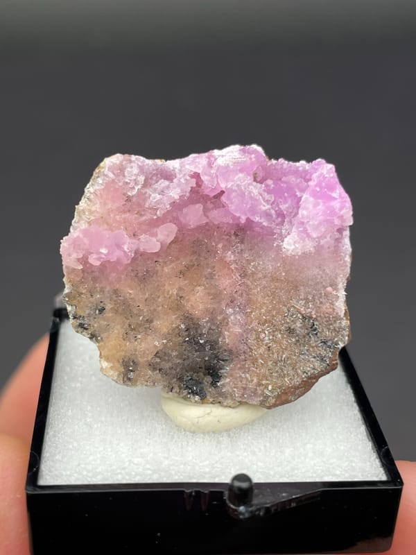 Magenta-pink botryoidal aragonite crust on pale slab from Yunnan, China, in a box, second angle