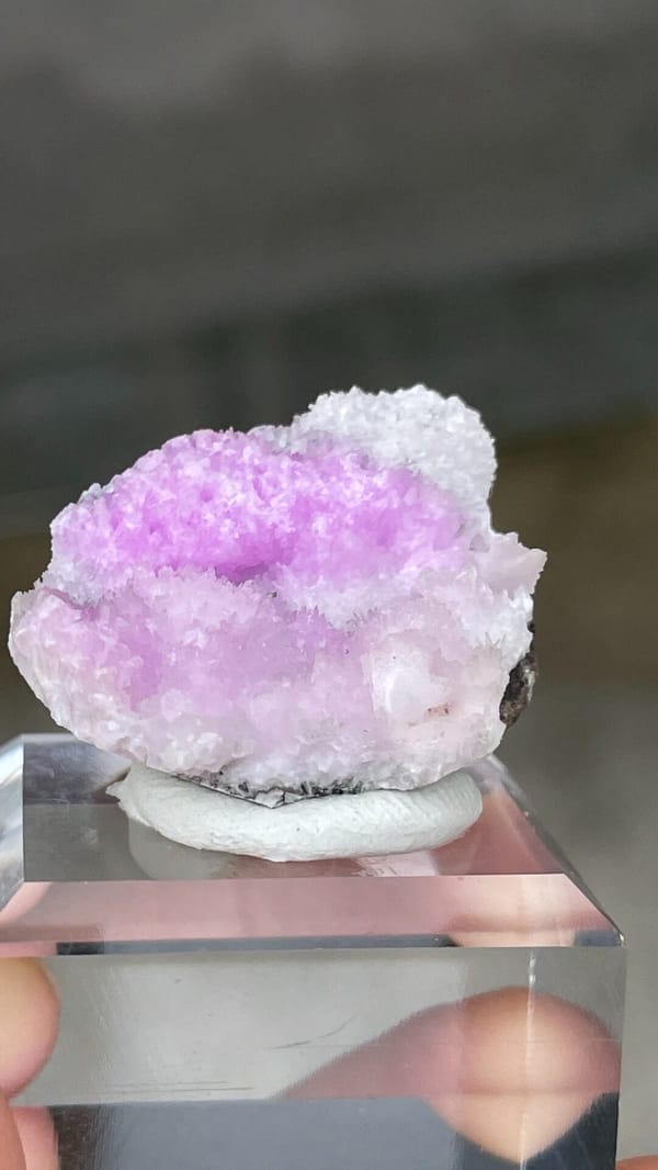Magenta-pink aragonite cap on pale rock from Yunnan, China, close-up of the crystal faces