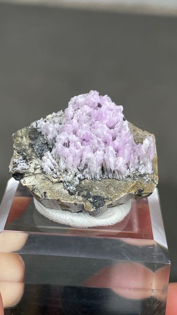 Pink-lilac aragonite crest on grey rock from Yunnan, China, on an acrylic stand