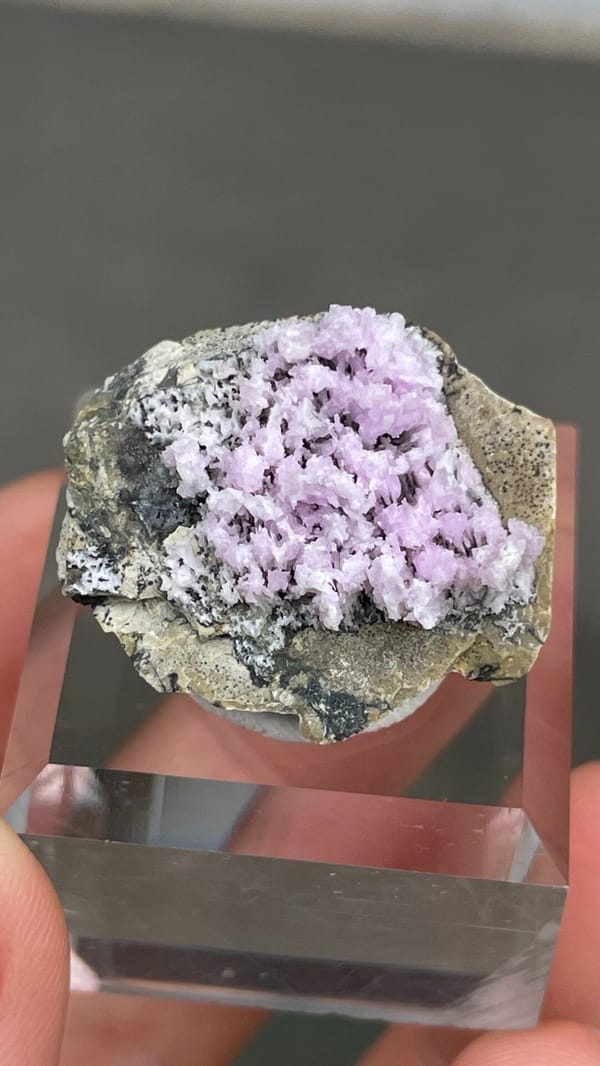 Pink-lilac aragonite crest on grey rock from Yunnan, China, on an acrylic stand, second angle