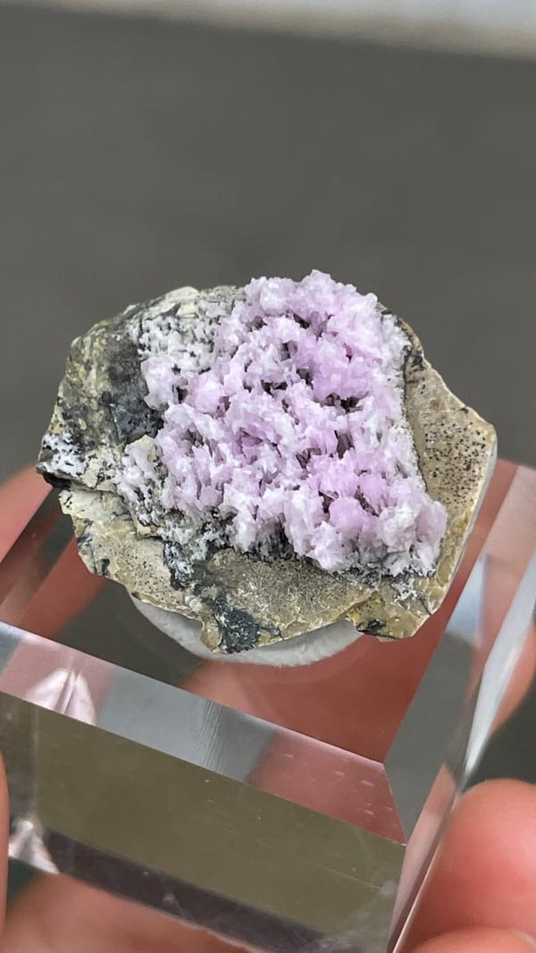 Pink-lilac aragonite crest on grey rock from Yunnan, China, on an acrylic stand, close-up of the crystal faces