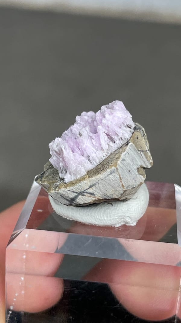 Pink-lilac aragonite crest on grey rock from Yunnan, China, on an acrylic stand, reverse side