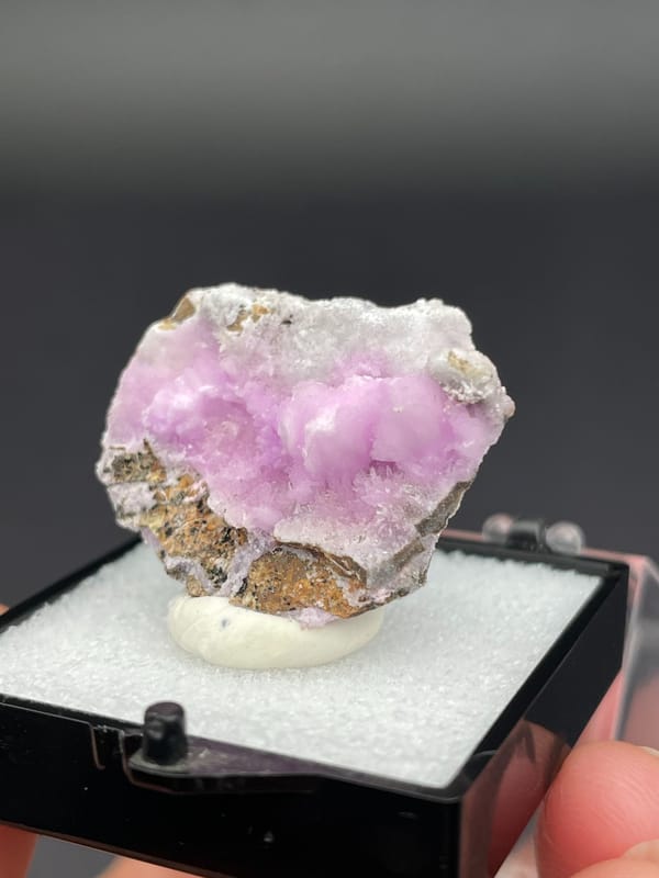 Pink-lilac botryoidal aragonite crust on pale slab from Yunnan, China, in a box, close-up of the crystal faces