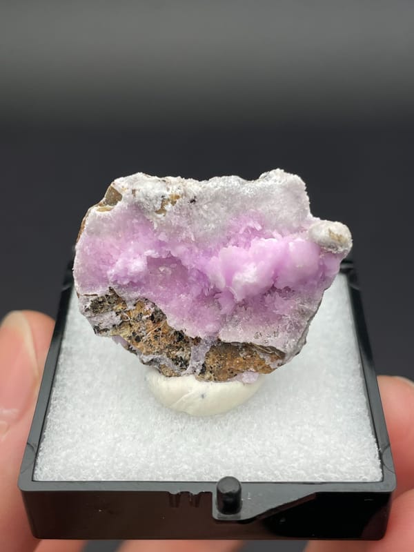 Pink-lilac botryoidal aragonite crust on pale slab from Yunnan, China, in a box, top view