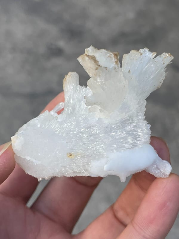 White fibrous aragonite spray from Guizhou, China, held in hand