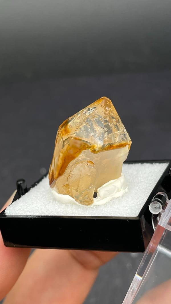 Amber caramel-coloured quartz crystal from Guangdong, China, in a display box, close-up of the crystal faces
