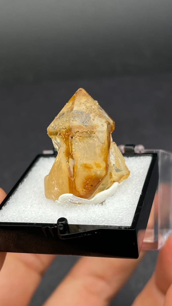 Amber caramel-coloured quartz crystal from Guangdong, China, in a display box, detail of the matrix contact