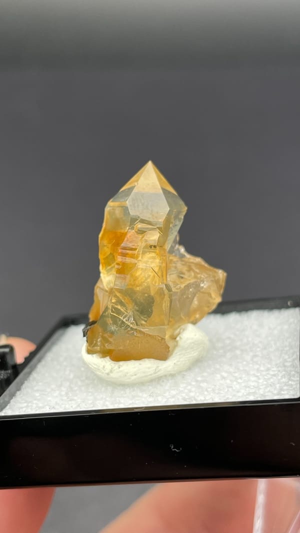 Caramel-brown transparent quartz crystal from Guangdong, China, in a display box, close-up of the crystal faces