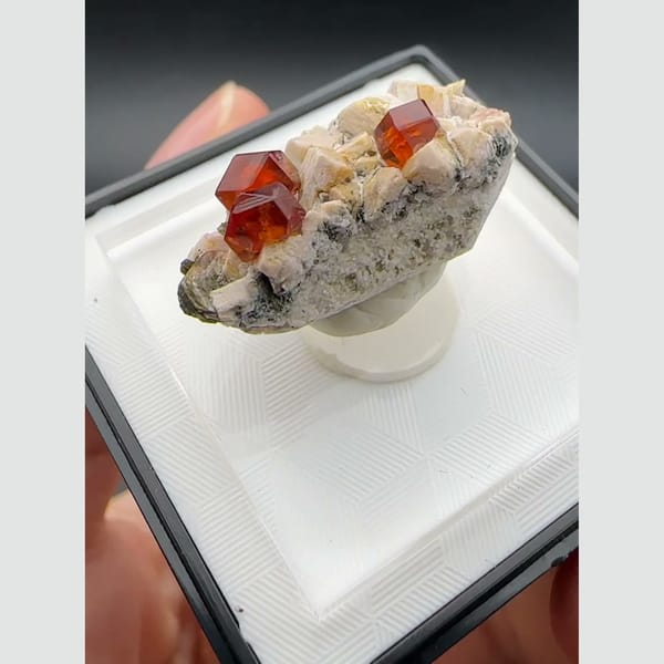 Orange-red spessartine garnet crystals on pale feldspar matrix from Yunxiao, Fujian, China — detail view