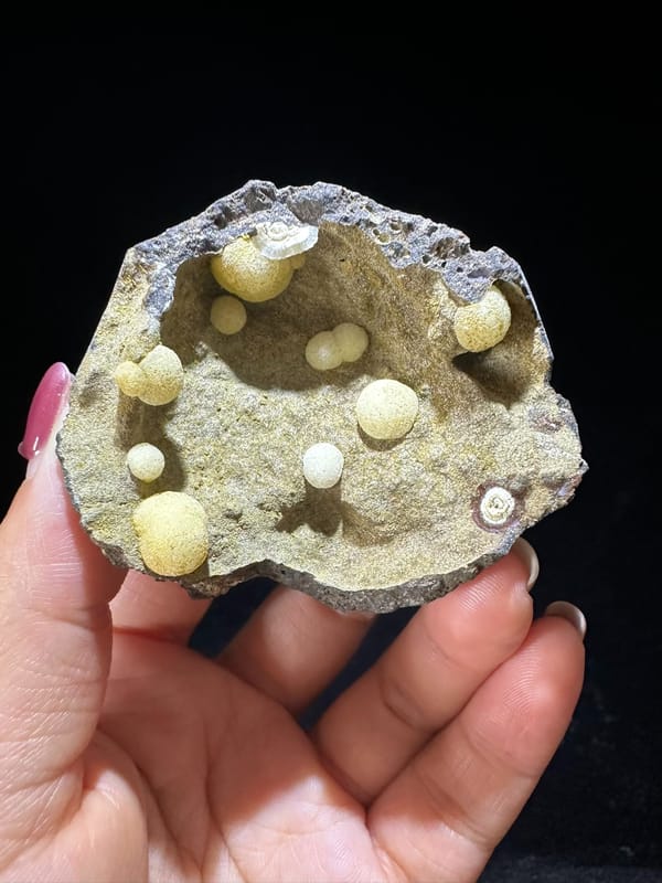 Cream calcite spheres inside a shallow rock cavity from Zhejiang China, specimen view 2