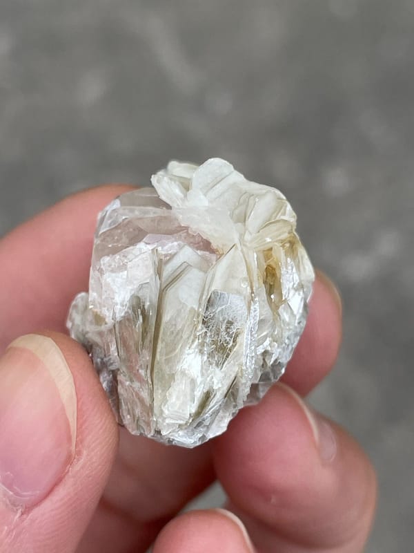 Pale pink apatite crystal surrounded by white mica blades from Pakistan, close-up of the crystal faces