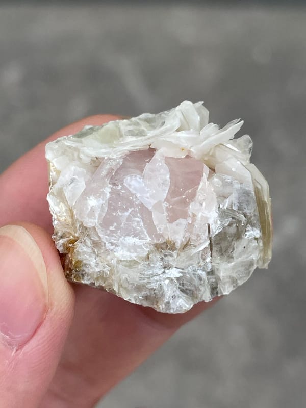 Pale pink apatite crystal surrounded by white mica blades from Pakistan, detail of the matrix contact