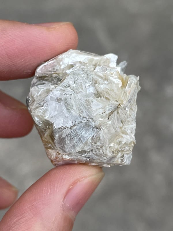 Pale pink apatite crystal surrounded by white mica blades from Pakistan, side view