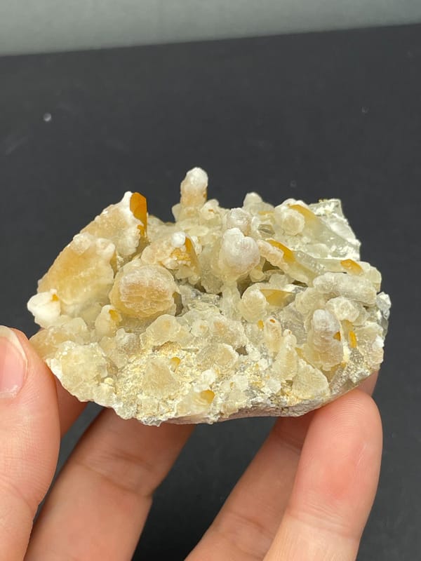 Cream-yellow citrine and calcite crust from Jinkouhe, Sichuan, China, held in hand