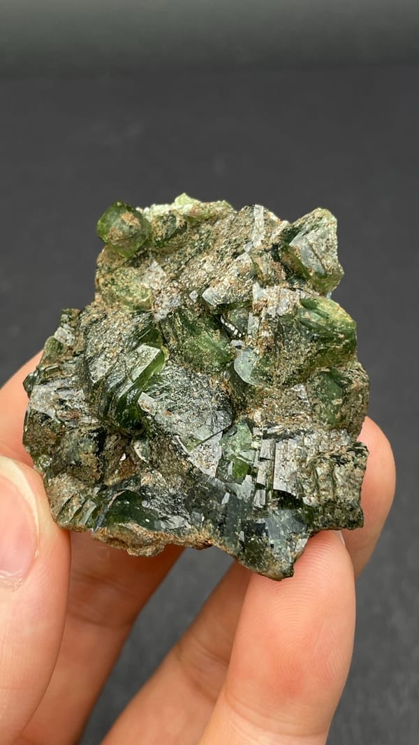 Apple-green ludlamite crystals on grey matrix from Brazil, close-up of the crystal faces