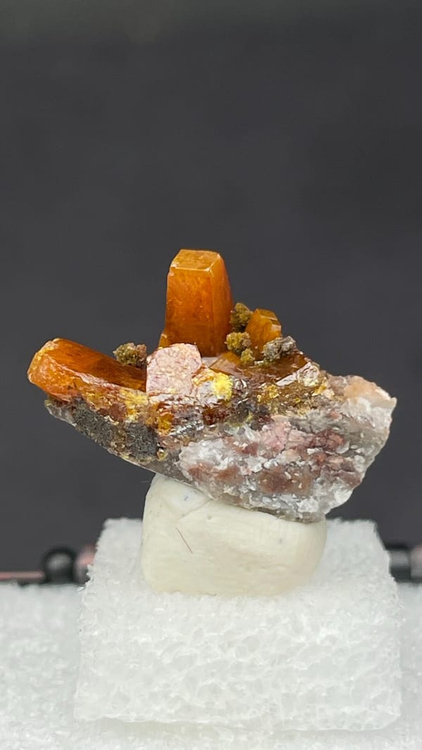 Bright orange wulfenite crystals on brown matrix from Mexico, in a display box
