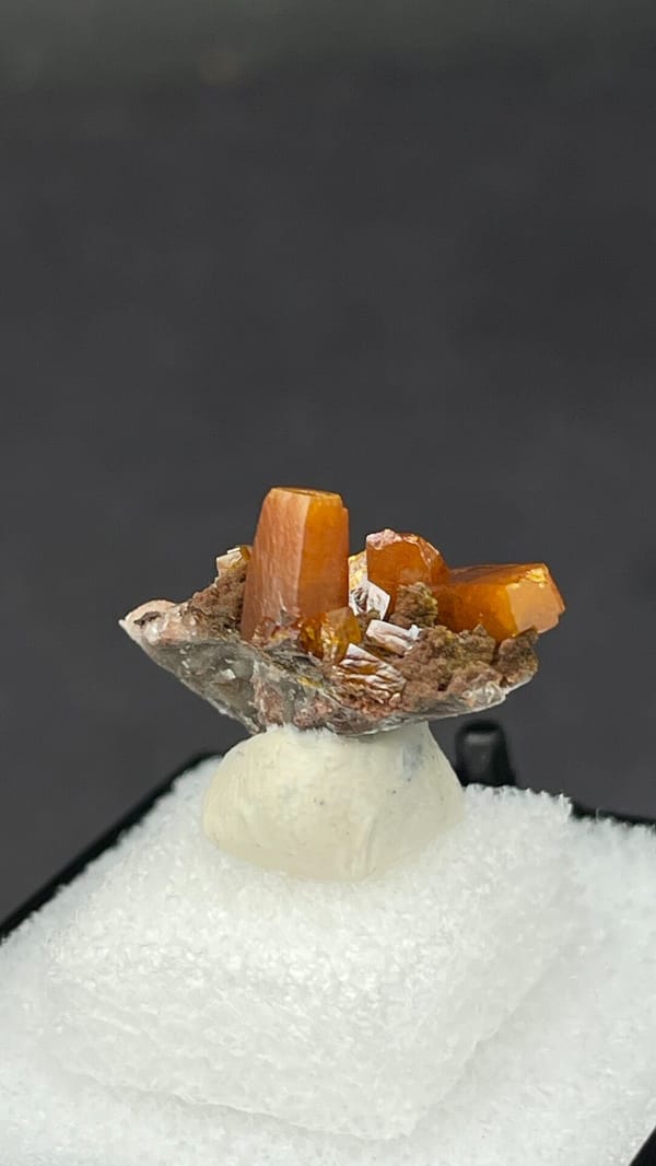 Bright orange wulfenite crystals on brown matrix from Mexico, in a display box, top view
