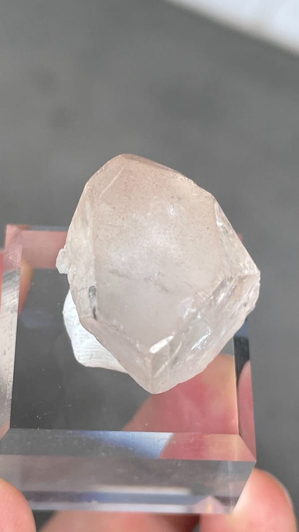 Colourless blocky topaz crystal from Yunnan, China, on an acrylic stand, reverse side
