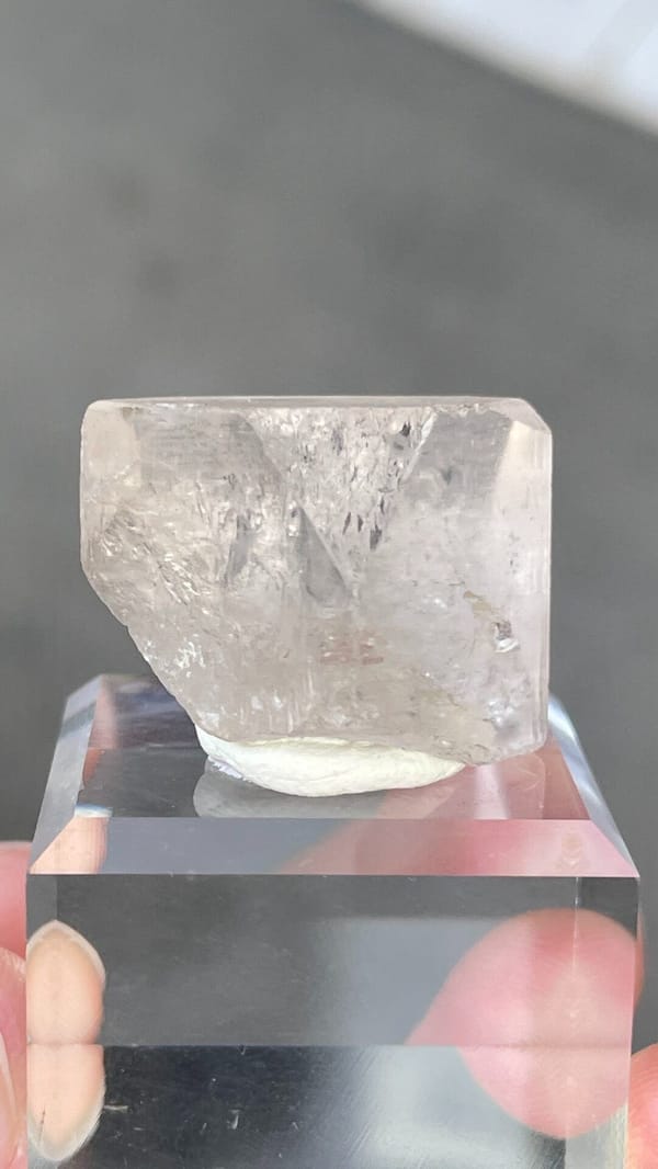 Colourless blocky topaz crystal from Yunnan, China, on an acrylic stand, detail of the matrix contact