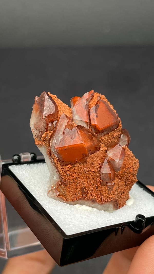 Red hematoid quartz with black specular hematite from Shanxi, China, in a perky box, close-up of the crystal faces