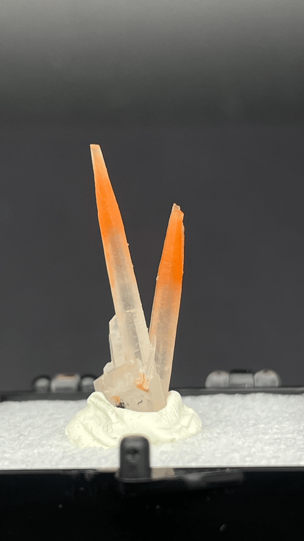 Two slender orange-red hematoid quartz needles from Guangdong, China, in a perky box