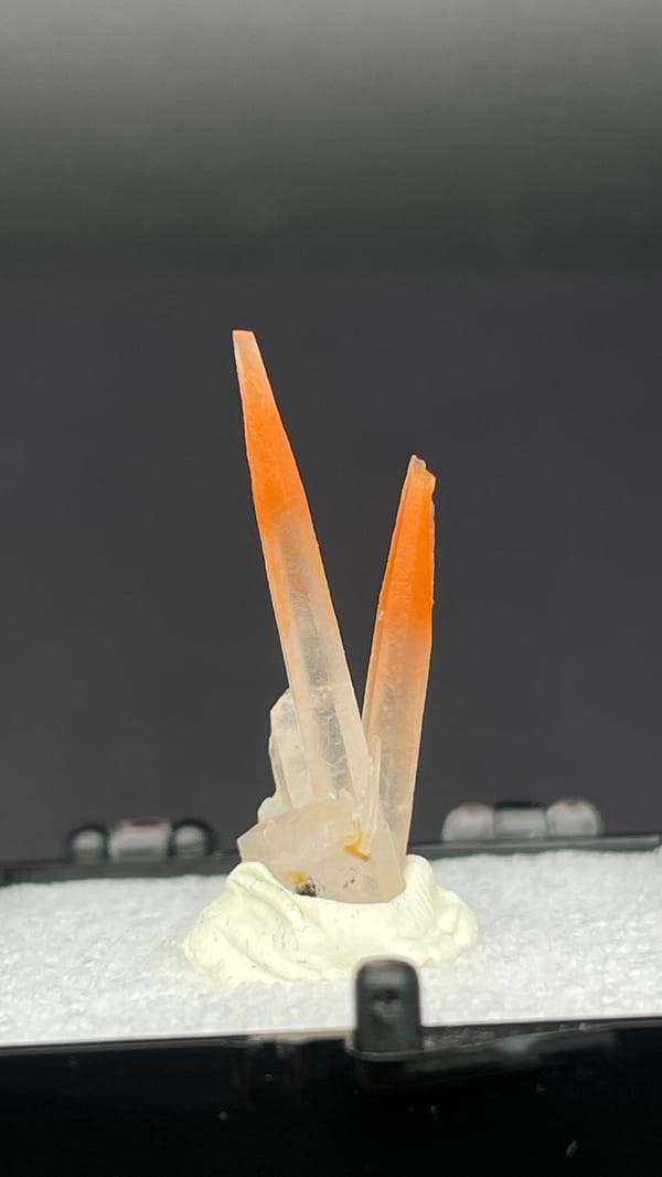 Two slender orange-red hematoid quartz needles from Guangdong, China, in a perky box, second angle