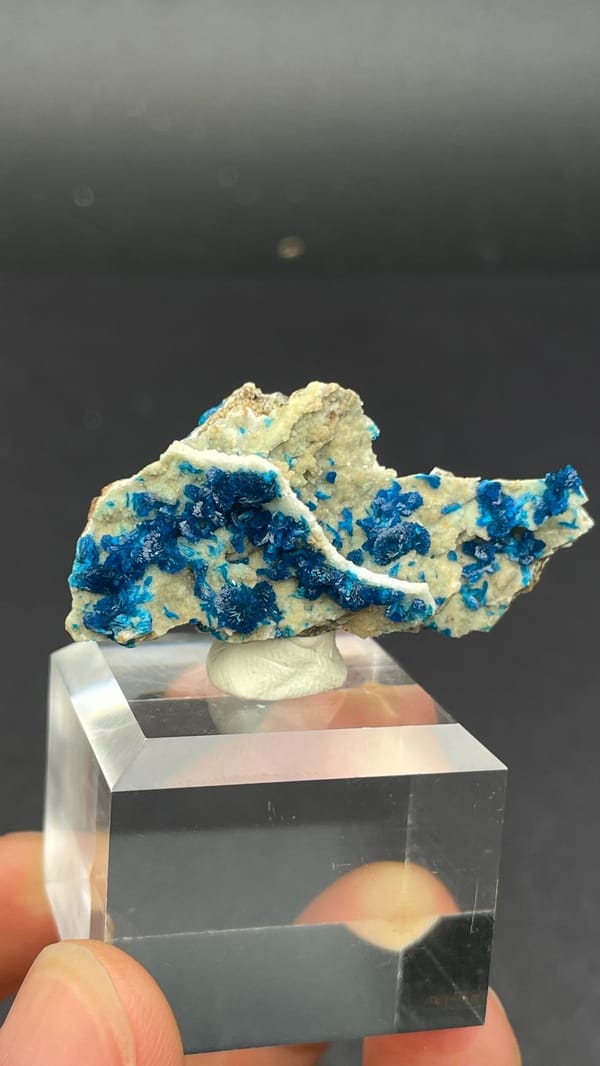 Deep blue veszelyite fan on cream matrix from Yunnan, China, on an acrylic stand, close-up of the crystal faces