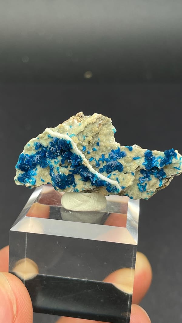 Deep blue veszelyite fan on cream matrix from Yunnan, China, on an acrylic stand, reverse side
