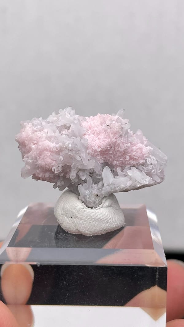 Pale pink rhodochrosite crust on quartz from Romania, on an acrylic stand, second angle