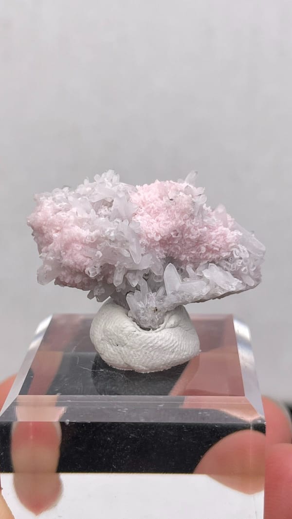 Pale pink rhodochrosite crust on quartz from Romania, on an acrylic stand, top view