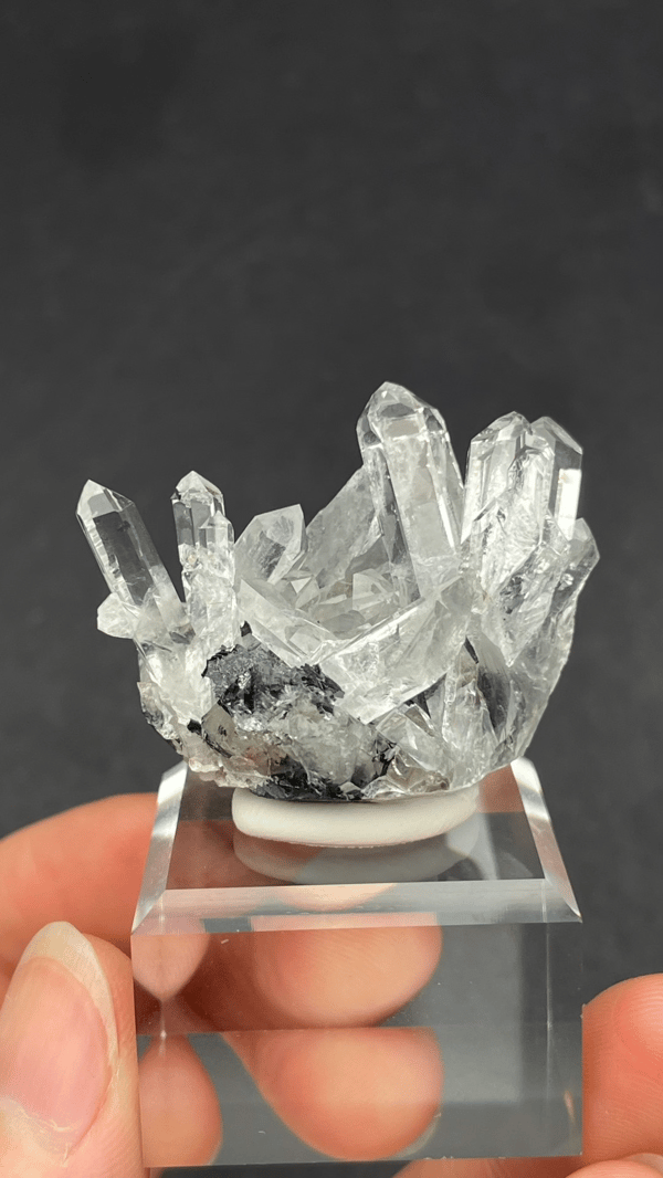 Long clear quartz points on specular hematite from Guangdong, China, on a stand