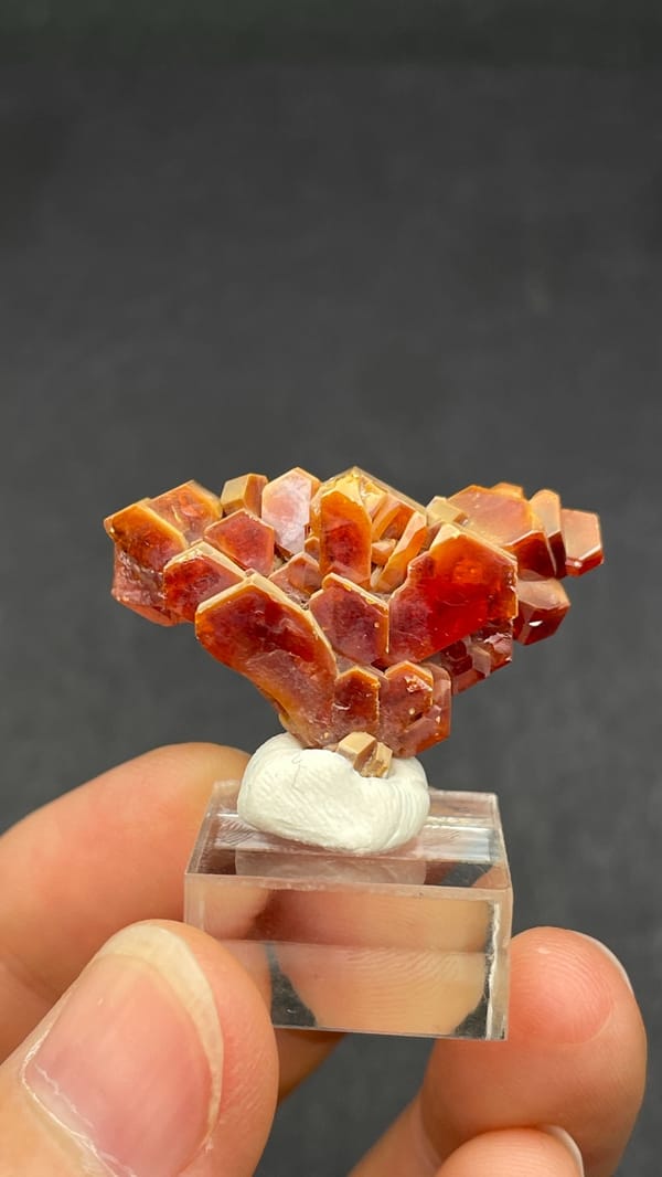 Branching deep red vanadinite crystal group from Morocco, on an acrylic stand, detail of the matrix contact