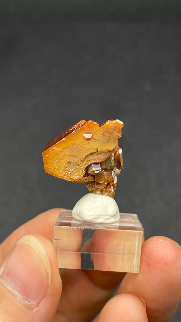 Dark red vanadinite crystal group from Morocco, on an acrylic stand, reverse side