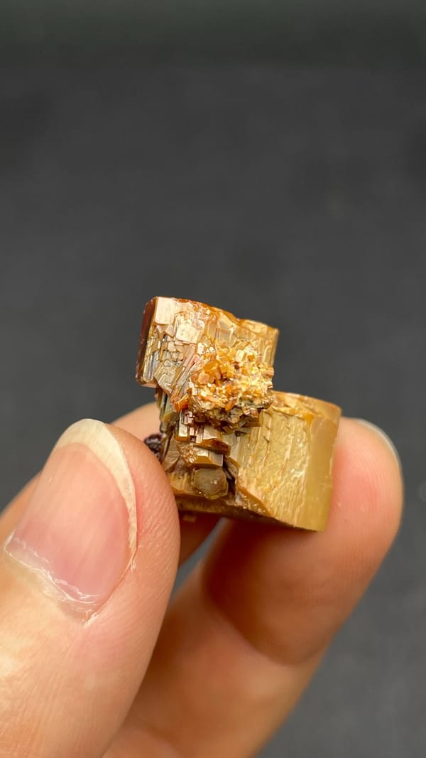 Dark red vanadinite crystal group from Morocco, on an acrylic stand, detail of the matrix contact