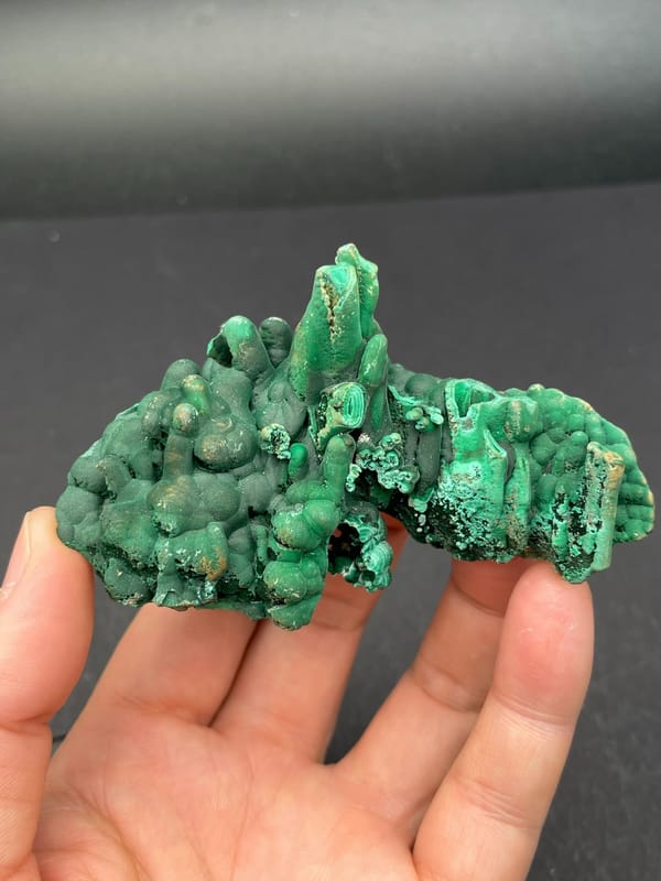 Emerald green botryoidal malachite from Yangchun, Guangdong, China, held in hand