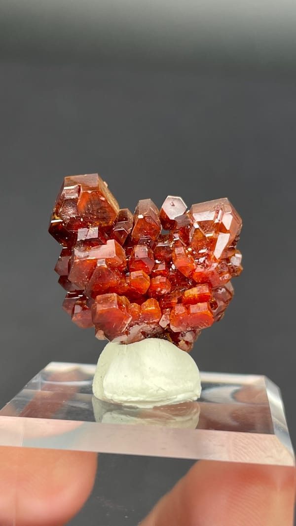Stacked apricot-orange vanadinite plates from Morocco on an acrylic stand, close-up of the crystal faces