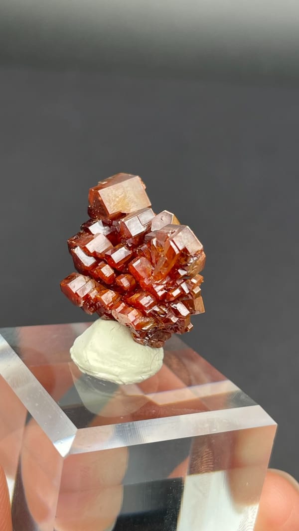 Stacked apricot-orange vanadinite plates from Morocco on an acrylic stand, top view