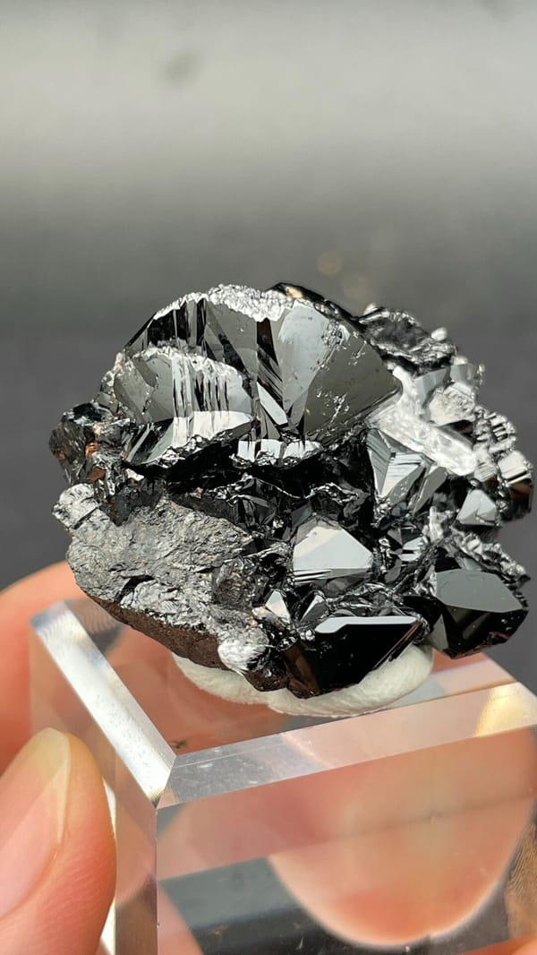 Black lustrous cassiterite with a clear quartz crystal from Xuebaoding, Sichuan, close-up of the crystal faces