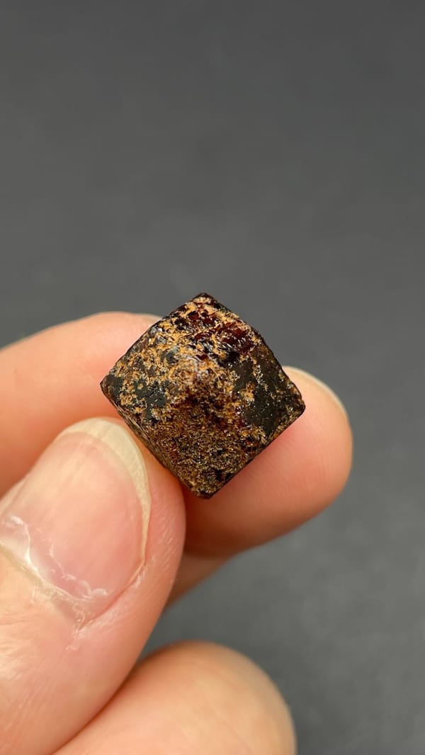 Dark brown dodecahedral andradite garnet crystal from Handan, Hebei, China, detail of the matrix contact