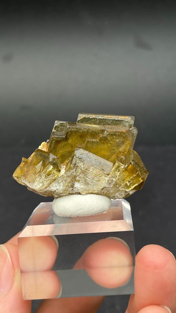 Amber-yellow tabular baryte crystals from Peru, on an acrylic stand, detail of the matrix contact
