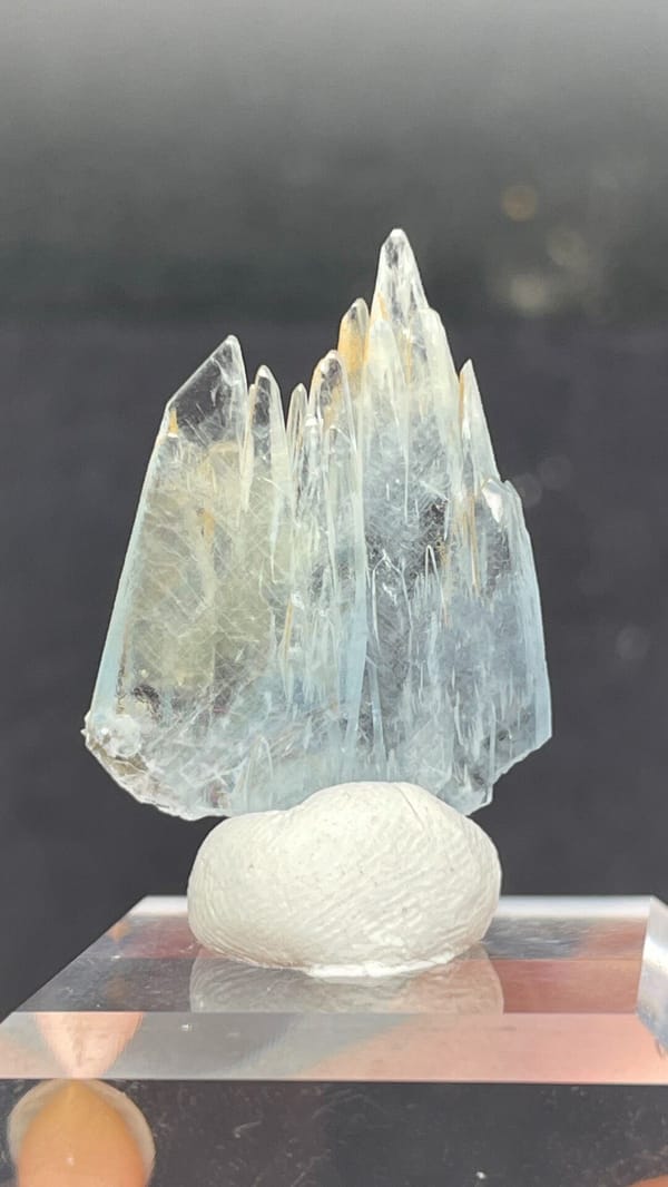 Pale blue transparent baryte blades from Morocco, on an acrylic stand, detail of the matrix contact