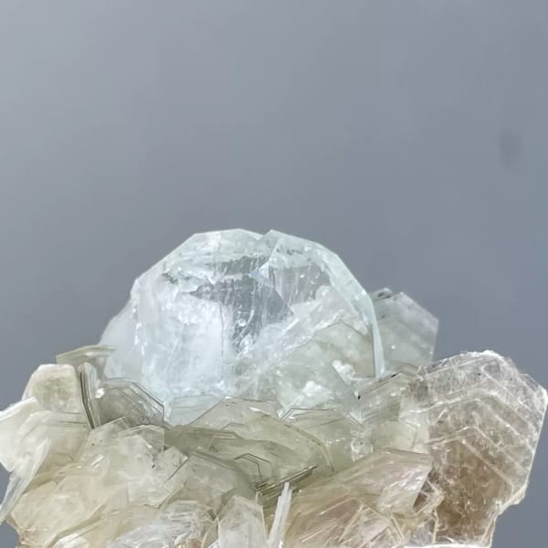 Pale blue Xuebaoding aquamarine crystal in a silvery mica rosette — complete view