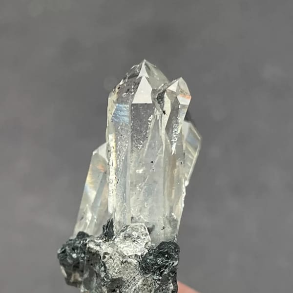 Water-clear quartz points on black specular hematite from Guangdong — alternate view