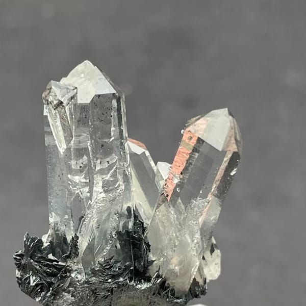 Water-clear quartz points on black specular hematite from Guangdong — alternate view