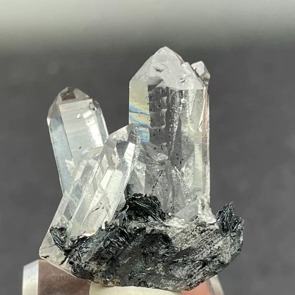 Water-clear quartz points on black specular hematite from Guangdong — detail view